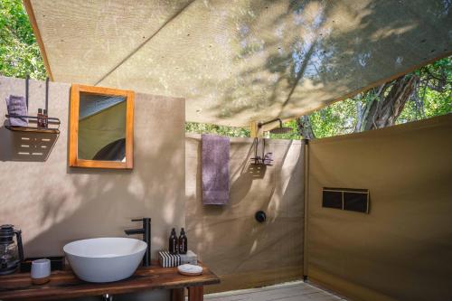a bathroom with a tub and a sink in a tent at Cha Cha Metsi in Maun