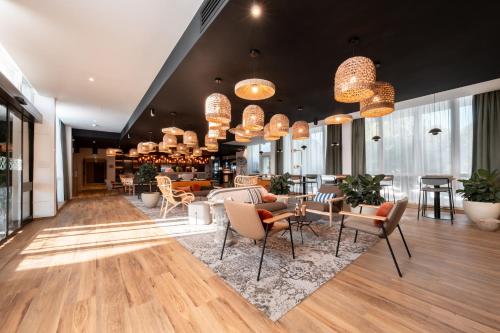 a lobby with chairs and tables and chandeliers at Novotel Chartres in Chartres