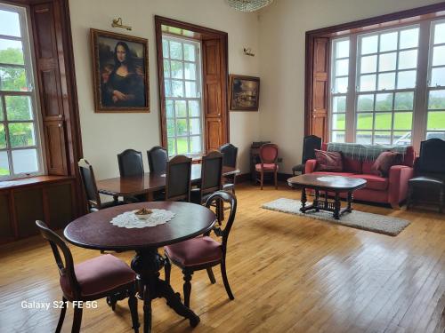 a living room with tables and chairs and a couch at Ballycurrin House in Galway
