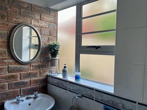 a bathroom with a sink and a mirror at Cenikma Guest Suites - Family Room 2 in East London