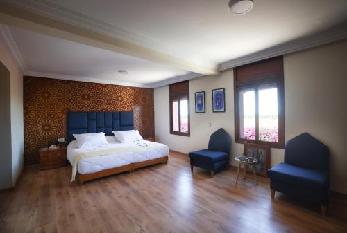a bedroom with a bed and two blue chairs at Villa Tizra - Guest house in AÃ¯n el Ksob