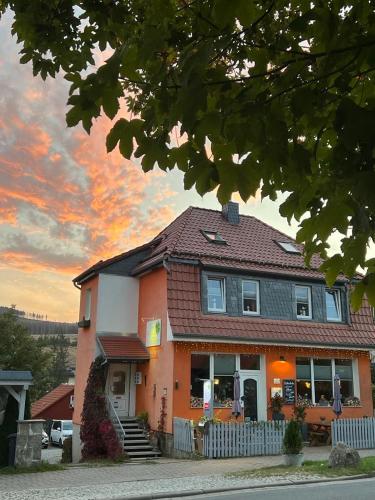 a orange and white house with a building at Pension Mühlhahn in Schierke