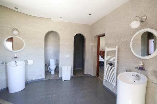 a bathroom with two sinks and two toilets and mirrors at Villa Tizra - Guest house in AÃ¯n el Ksob