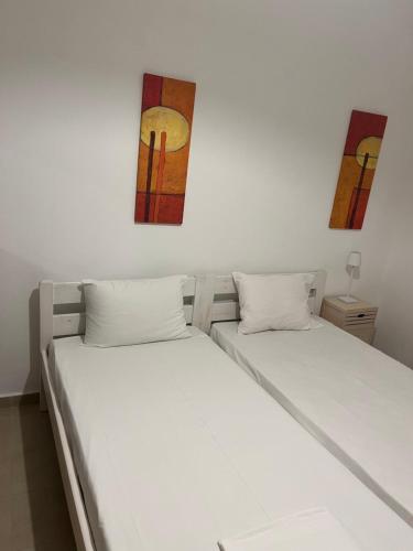 dwa łóżka w pokoju z dwoma obrazami na ścianie w obiekcie Nikotsaras beach house since 1930 w Acharavi