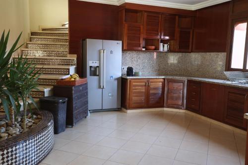 a kitchen with a refrigerator and wooden cabinets at Villa Tizra - Guest house in AÃ¯n el Ksob