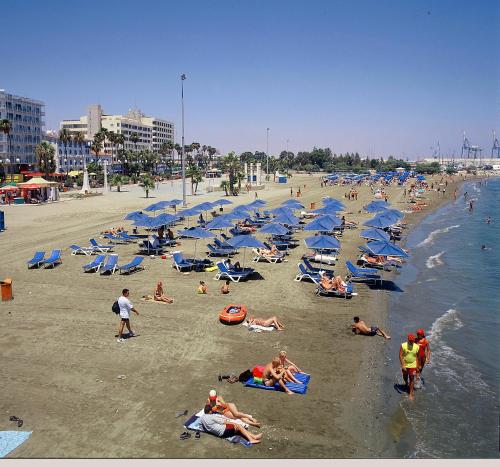 a group of people on a beach with blue umbrellas at Blazer Residence in Larnaka