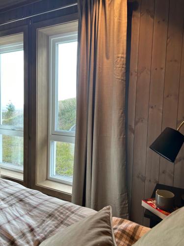 a bedroom with a bed and two windows at Bualie Golsfjellet in Gol