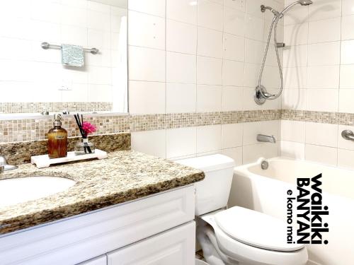 Baño blanco con aseo y lavamanos en Stunning 1BD a block away to Waikiki Beach Free Parking, en Honolulu