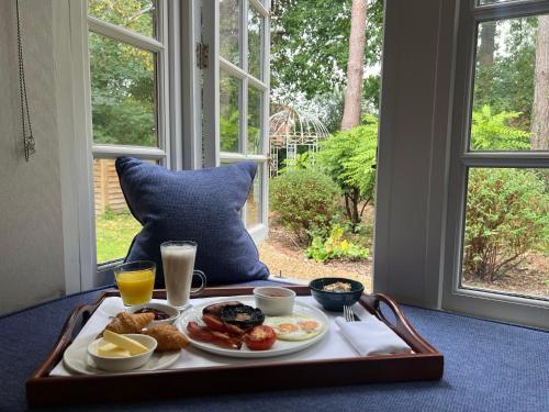 a tray with breakfast foods on a table with a window at Langshott Manor - Luxury Hotel Gatwick in Horley