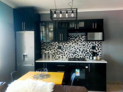 a kitchen with black cabinets and a wooden table at Elite Escape in Cape Town
