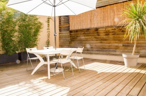 einen weißen Tisch und Stühle mit einem Sonnenschirm auf einer Terrasse in der Unterkunft Bel appartement moderne avec patio à Saint-Michel (Bordeaux) in Bordeaux