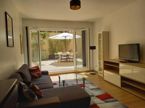 uma sala de estar com um sofá e uma televisão em Bel appartement moderne avec patio à Saint-Michel (Bordeaux) em Bordéus