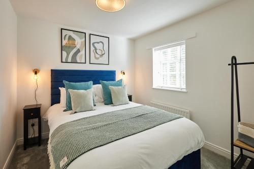 a bedroom with a large bed with a blue headboard at Host & Stay - Sandstone Cottage in Skelton