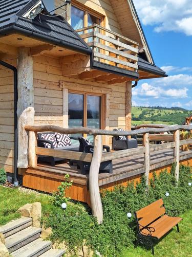 Cabaña de madera con banco en el porche en DOMEK NA WIERCHU en Kluszkowce