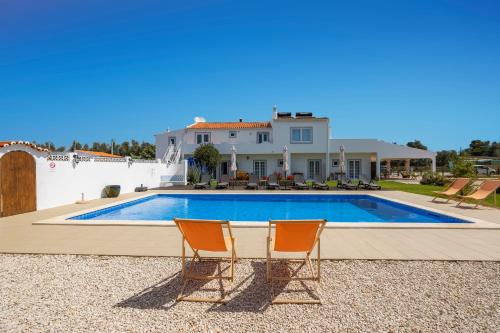 una casa con piscina e due sedie di Casa Jardim Oasis a Lagoa