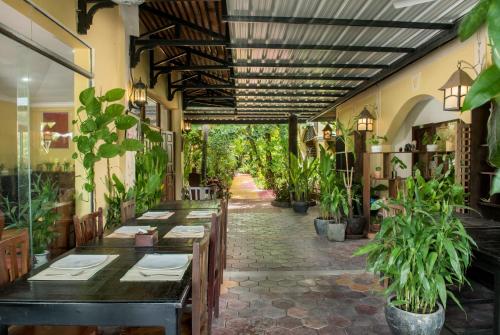un ristorante con tavoli e piante in vaso in un corridoio di Marirath Boutique Hotel a Siem Reap