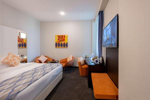 um quarto de hotel com uma cama e uma televisão de ecrã plano em Ramada Encore Doha by Wyndham em Doha