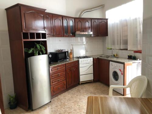 a kitchen with wooden cabinets and a stainless steel refrigerator at Tarrafal Ecodécor Full House in Tarrafal