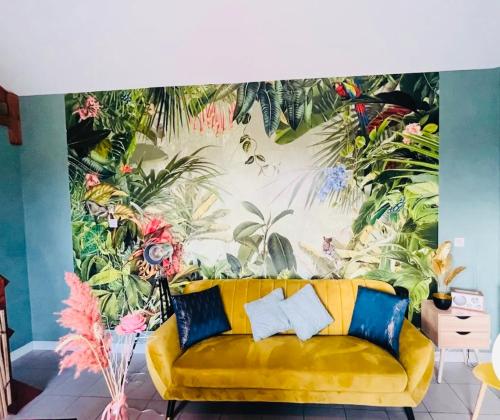 a yellow couch in a room with a tropical mural at Gîte de la Prévosserie in Rinxent