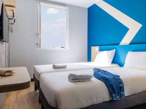 2 camas en una habitación con una pared azul en Hotel ibis budget Chatillon Paris Ouest, en Châtillon