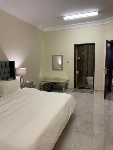 a bedroom with a large white bed and a bathroom at شقة فندقية عوائل ثلاث غرف نوم وغرفة معيشة ومطبخ ومدخل خاص in Riyadh Al Khabra