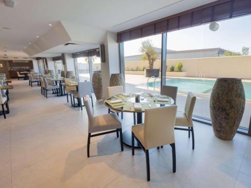 a dining room with tables and chairs and a pool at Mercure Alger Palais Des Congres in Alger