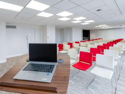 a laptop on a table in a room with chairs at Mercure Alger Palais Des Congres in Alger