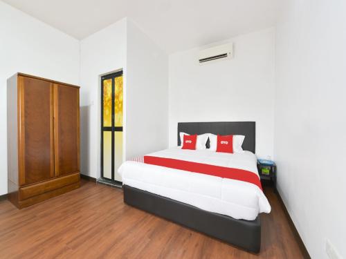 雪邦的住宿－OYO 90869 Hotel Madeena Inn，一间卧室配有一张带红色枕头的大床