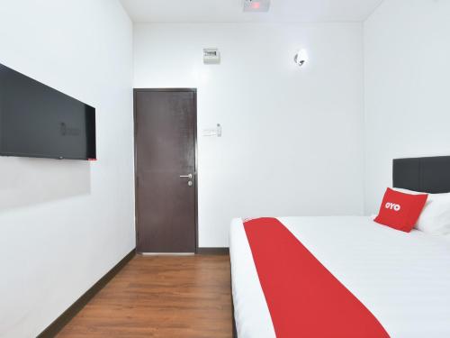 雪邦的住宿－OYO 90869 Hotel Madeena Inn，一间卧室配有一张带红色毯子的床和一台电视。