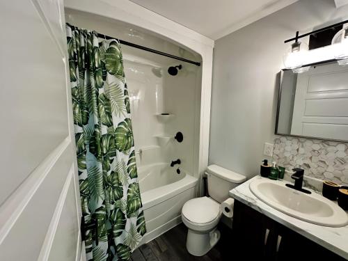 a bathroom with a sink and a toilet and a shower curtain at Palm Suite St Johns - Luxury One Bedroom Apartment in St. John's