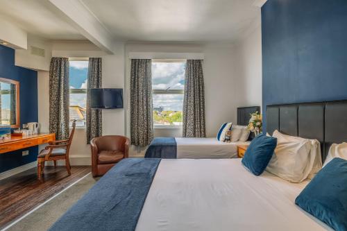 a hotel room with two beds and a desk at Muthu Westcliff Hotel (Near London Southend Airport) in Southend-on-Sea