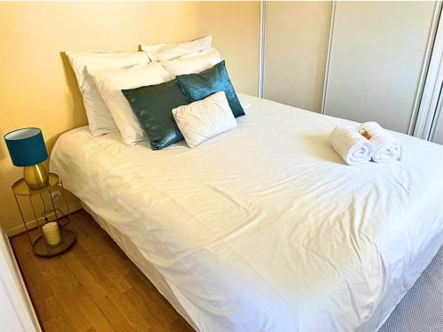 ein großes weißes Bett mit zwei gewalzten Handtüchern darauf in der Unterkunft Appart cosy rénové avec AC Hypercentre Nemours in Nemours