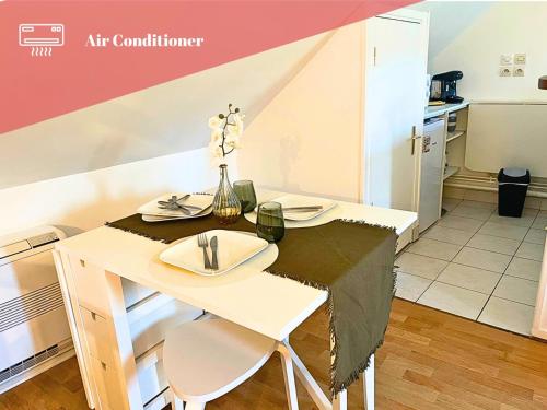 a small kitchen with a table with plates and flowers on it at Appart cosy rénové avec AC Hypercentre Nemours in Nemours