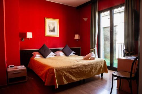 a bedroom with red walls and a bed with orange sheets at Hotel Berlino in Milan