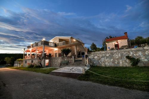 a large house with a stone wall next to a street at Villa Bella in Kruševo