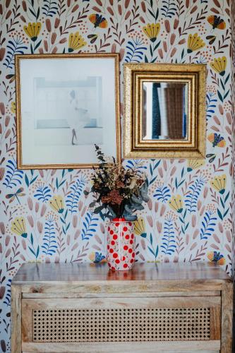 a vase of flowers on a table with two pictures at Hanley House in Tenbury