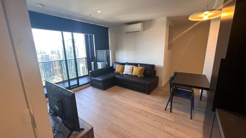a living room with a couch and a table and a television at Nest Apartments MEET Empire in Melbourne