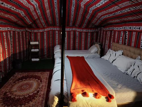 a bed in a room with a striped wall at Hamood desert local camp in Al Wāşil