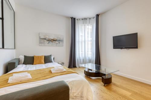 een slaapkamer met een groot bed en een flatscreen-tv bij Chic and Warm 1 bd Flat - Heart of the Luxury 16th in Parijs