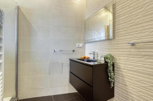 een badkamer met een wastafel en een spiegel bij Chic and Warm 1 bd Flat - Heart of the Luxury 16th in Parijs