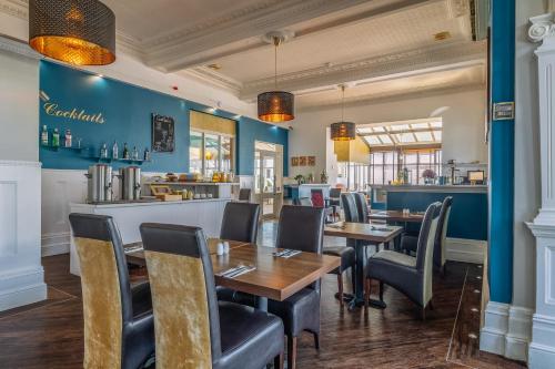 um restaurante com paredes azuis, mesas e cadeiras em Muthu Westcliff Hotel (Near London Southend Airport) em Southend-on-Sea