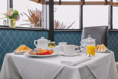 a white table with breakfast foods and orange juice at Muthu Westcliff Hotel (Near London Southend Airport) in Southend-on-Sea