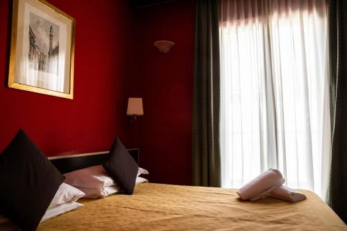 a bedroom with a bed with red walls and a window at Hotel Berlino in Milan