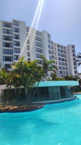 a pool with palm trees in front of a building at Umhlanga Breakers Resort in Durban