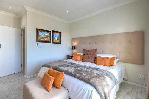 a bedroom with a large bed with orange pillows at Thyme Wellness Spa and Guesthouse in Cape Town