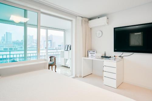 a white bedroom with a large window and a tv at Garosugil Homestay - Female Only in Seoul