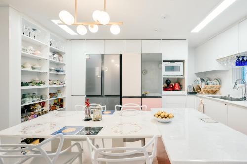 a white kitchen with a white table and chairs at Garosugil Homestay - Female Only in Seoul