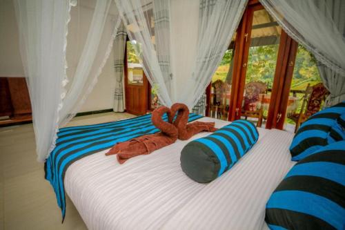 a bed with two brown towels on top of it at Blue Heaven Cottage in Ella