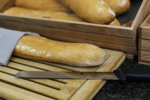 a loaf of bread on a cutting board with a knife at Hotel Berlino in Milan