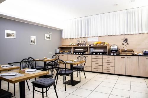 a restaurant with tables and chairs and a kitchen at Hotel Berlino in Milan